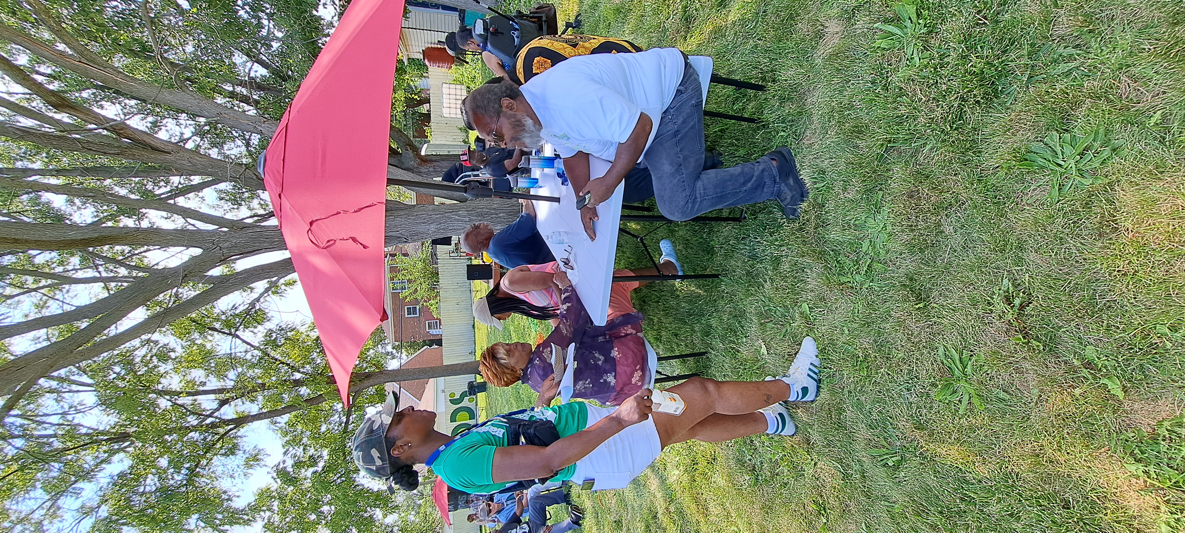 YWCO president Mose Primus sits at a parkbench, in conversation with a nearby resident.