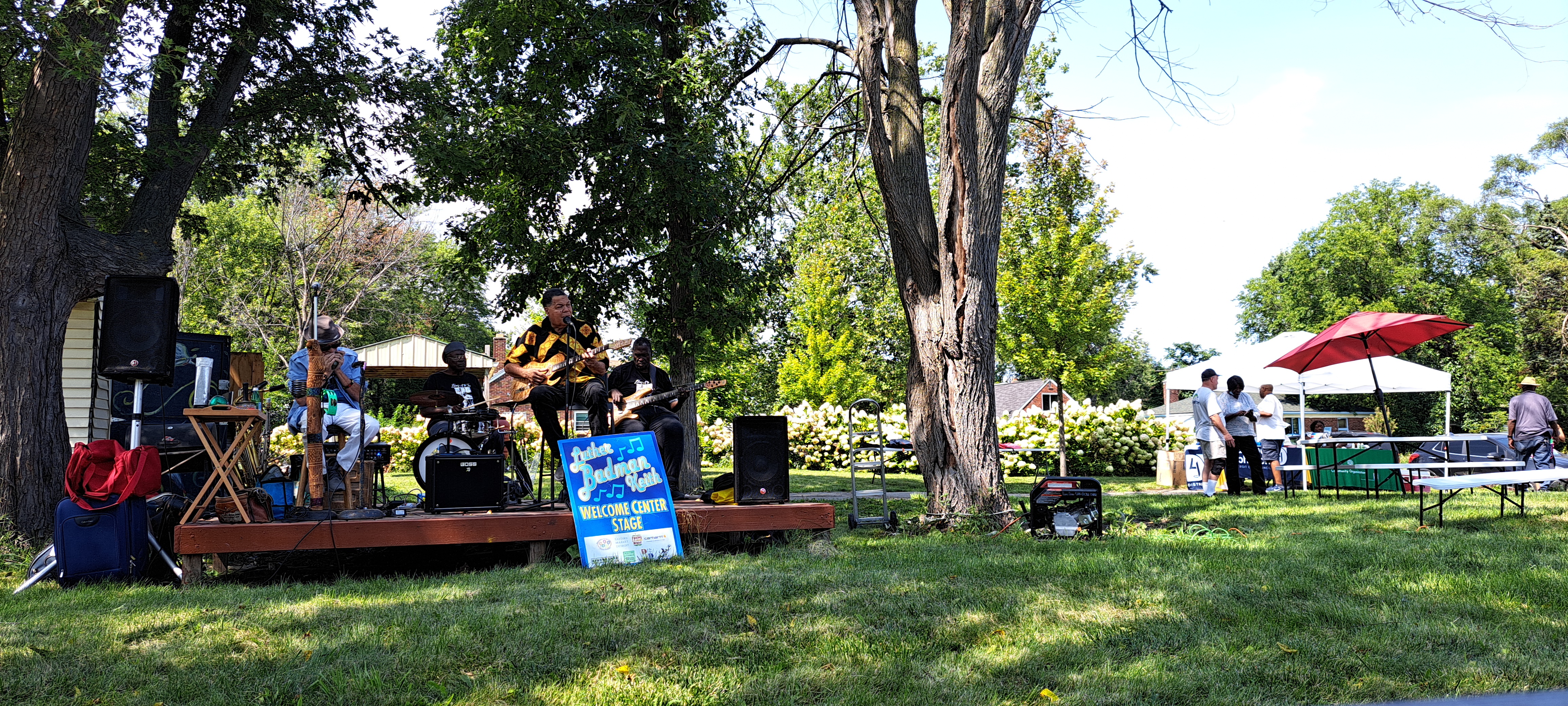 Four musicians play intensely on a stage. A frontman displays emotive vocals and guitarwork while other members play harmonica, drums, and bass guitar.