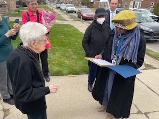 On the walk leading to her house, Councilwoman Johnson's office representative presents proclamation to Ms. Lottie. Nearby, attendees take pictures.
